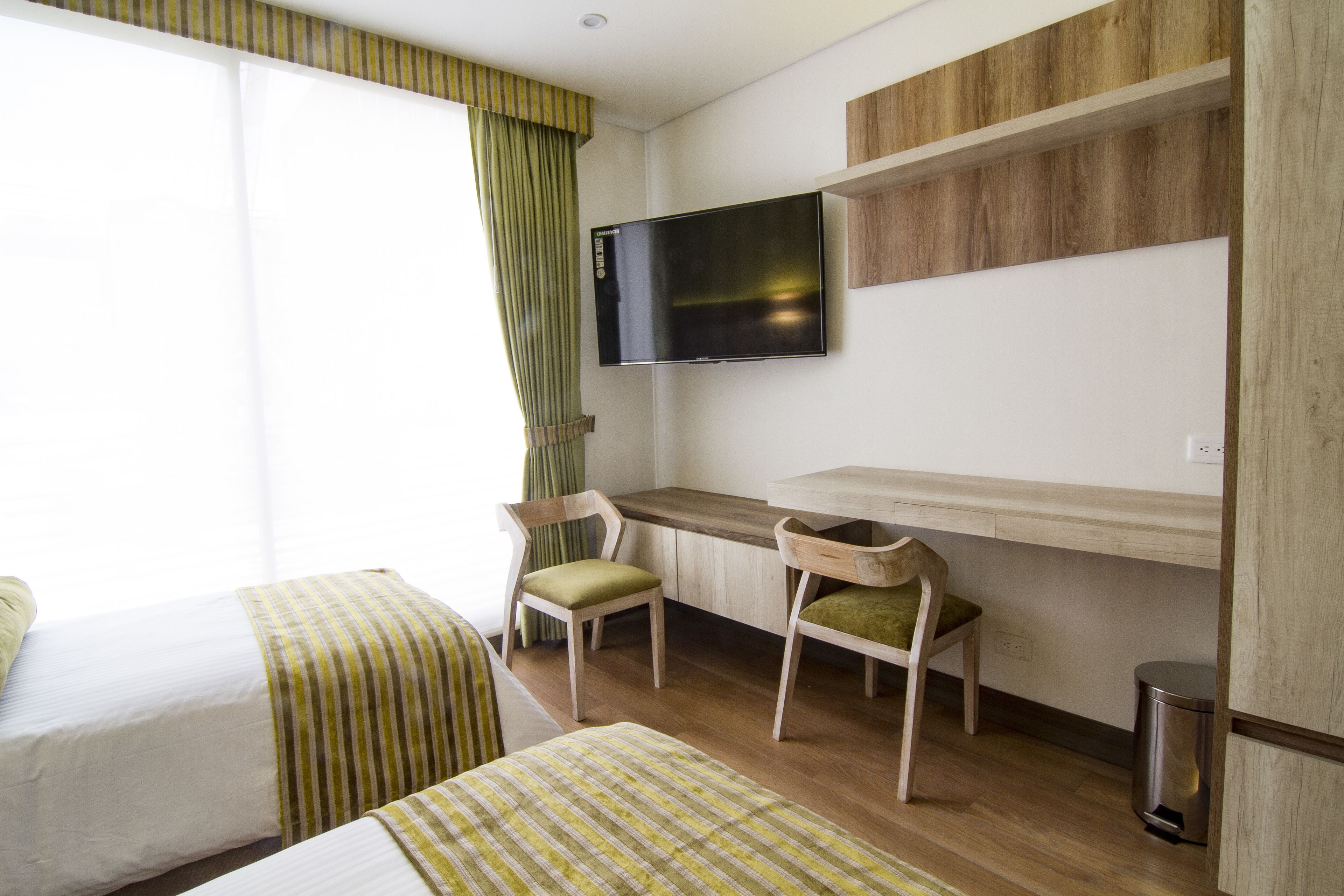 Ein Hotelzimmer mit zwei Betten, einem Schreibtisch, einem Stuhl, einem Fernseher und einem Papierkorb.