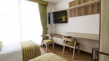 Ein Hotelzimmer mit zwei Betten, einem Schreibtisch, einem Stuhl, einem Fernseher und einem Papierkorb.