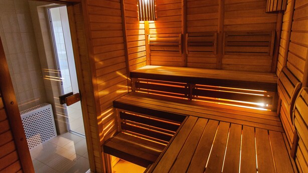 A sauna with wooden walls and benches, a sloped ceiling, and a small window. - De Película Apartasuites (Bogotá)