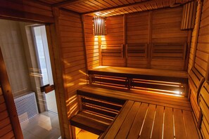 A sauna with wooden walls and benches, a sloped ceiling, and a small window. - De Película Apartasuites (Bogotá)