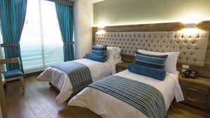 A hotel room with two beds, a wooden headboard, a bedside table with a phone, and a chair. - De Película Apartasuites (Bogotá)