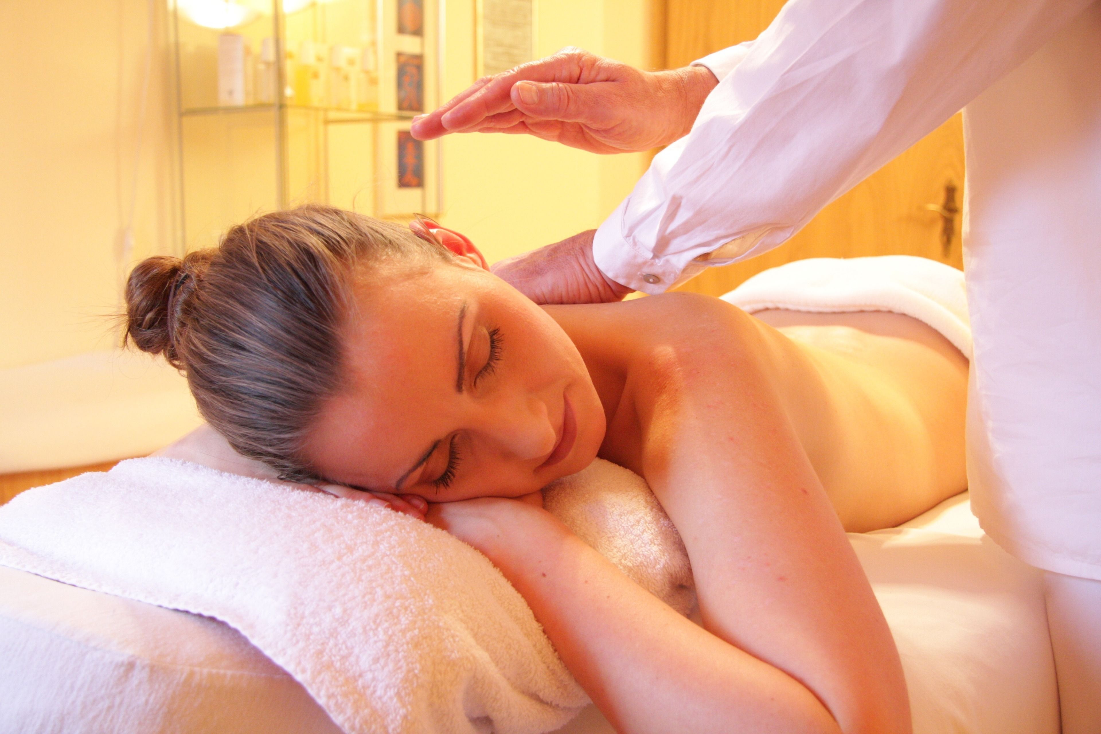 A person receiving a massage in a room with a white towel and a massage table.
