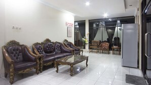 A living room with a two-seater sofa, a glass coffee table, and a dining area with a table and chairs. - RedDoorz Plus near Stadion Mandala Krida (Yogyakarta)