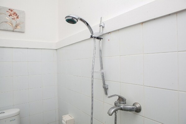 Ducha con cabezal de ducha manual y grifo empotrado en un baño con baldosas blancas.