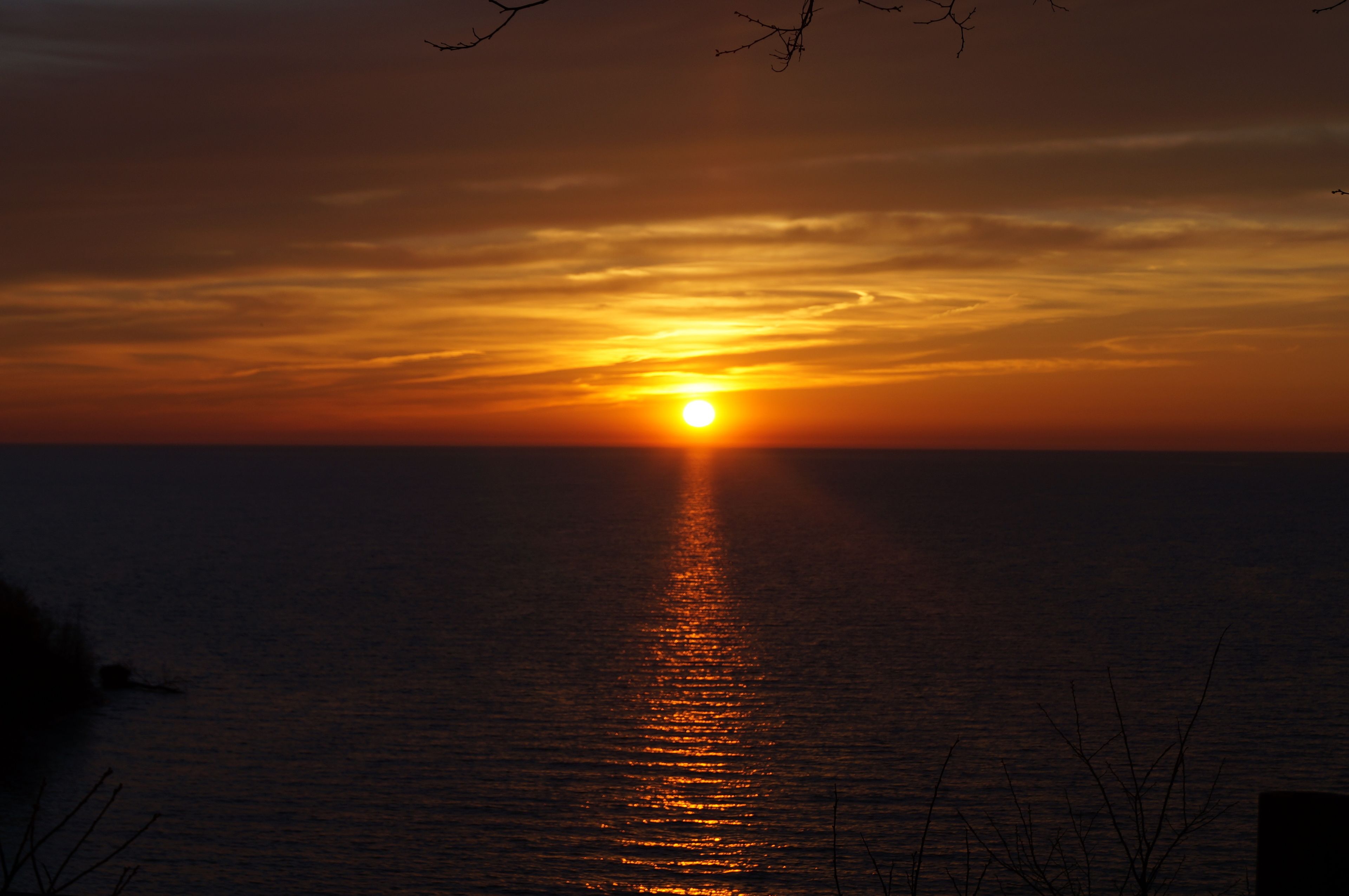 A sunset over a calm sea with a visible horizon line.