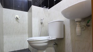 A bathroom with a toilet, a sink, and a shower. - RedDoorz @ Swakarya Kaliurang (Depok)