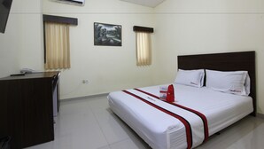 A hotel room with a bed, a desk, an air conditioner, and a painting on the wall. - RedDoorz @ Swakarya Kaliurang (Depok)