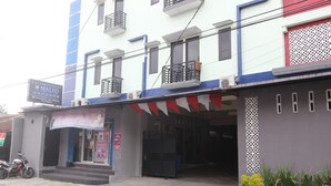 A building with a storefront, a motorcycle parked outside, and a signboard. - RedDoorz @ Swakarya Kaliurang (Depok)
