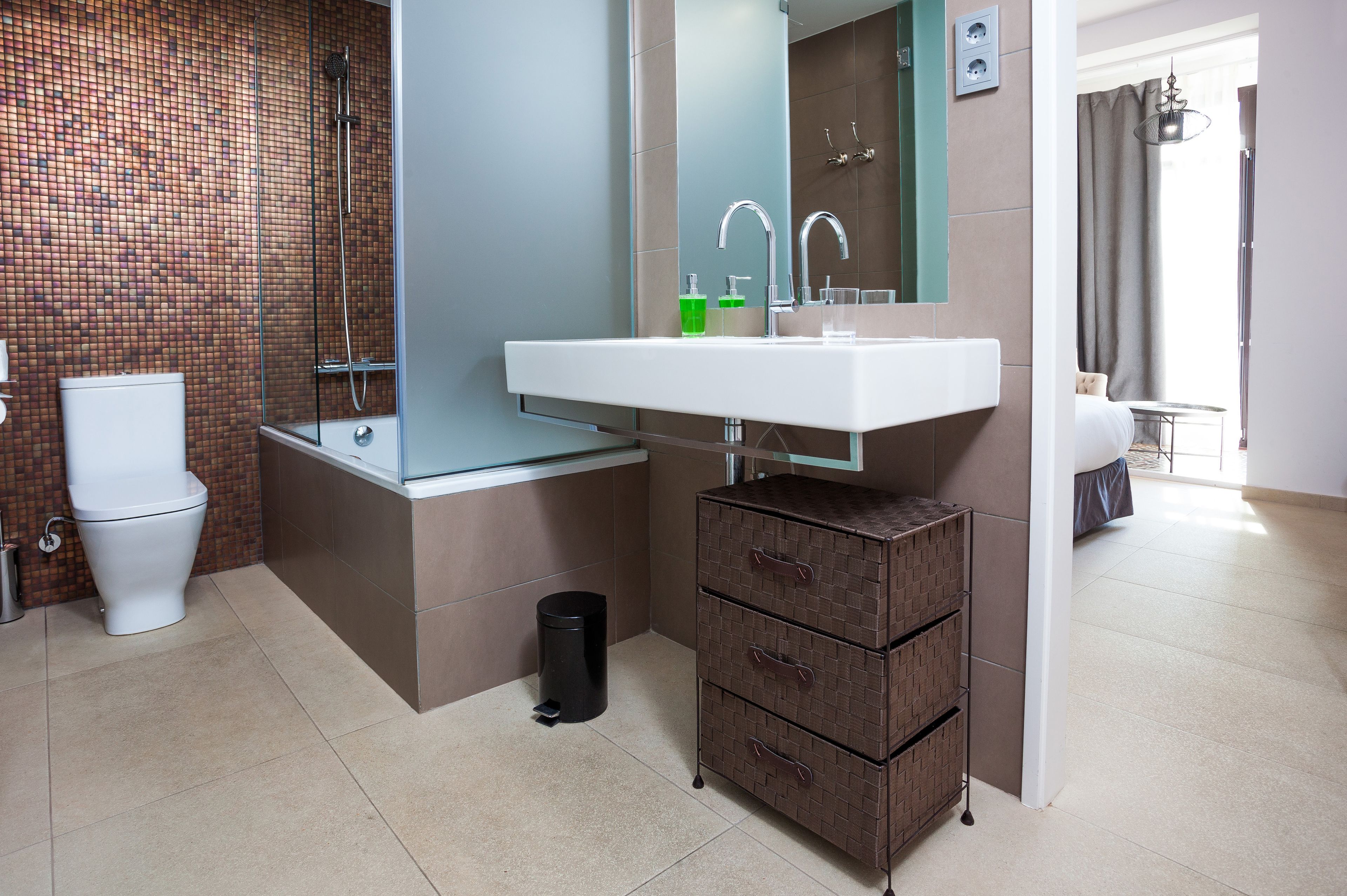 A modern bathroom with a glass shower enclosure, a white sink, and a mirror above it.