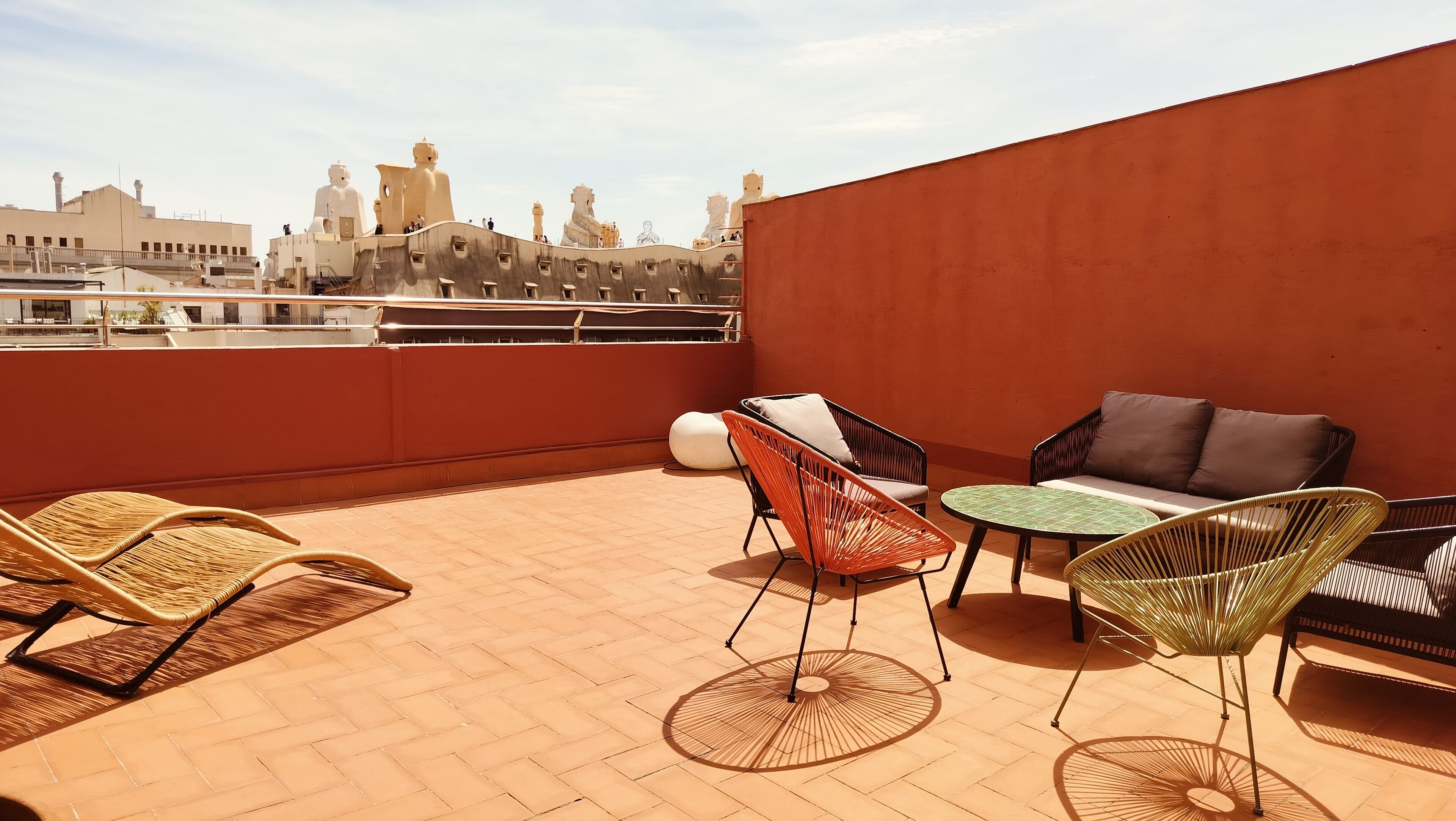 Una terraza en la azotea con sillas de mimbre, una mesa redonda y un sofá.