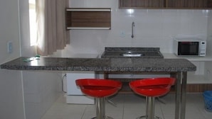 Eine Küche mit einer Granit Arbeitsplatte, zwei roten Barhocker, einer Mikrowelle und Holzschränken.