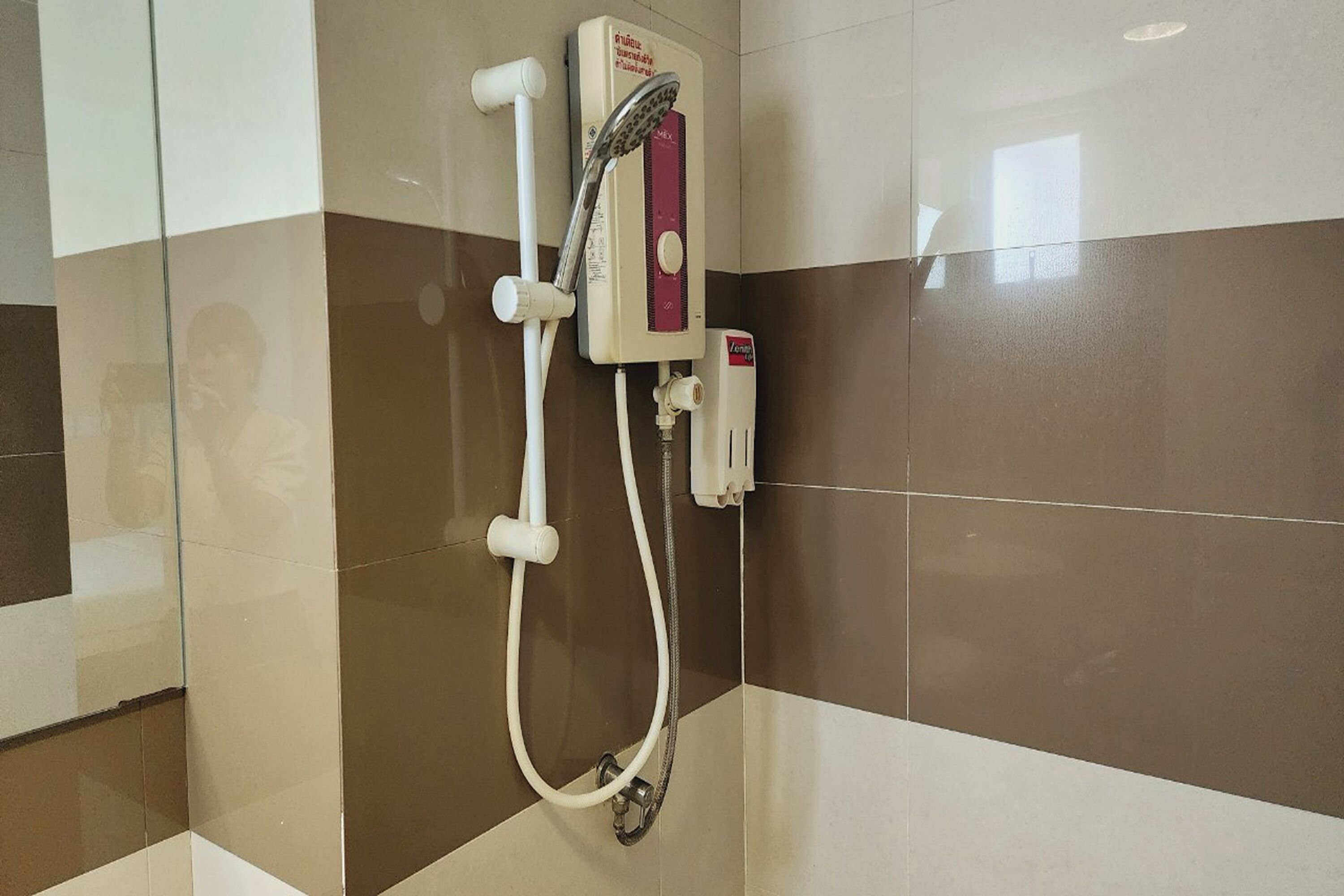 Eine Dusche mit Handbrause und Bedienfeld an der Wand.