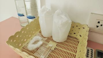 A yellow woven basket containing a white brush, a pair of white socks, and a small card on a pink surface.