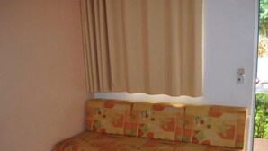 A small, enclosed seating area with a patterned cushion and a window with curtains. - Apartment diRoma Fiori - Achei Férias (Caldas Novas)