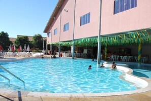 A swimming pool with a poolside area, lounge chairs, and umbrellas. - Apartment diRoma Fiori - Achei Férias (Caldas Novas)
