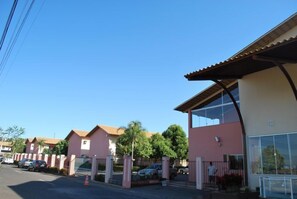A row of pink buildings with large windows and a covered walkway. - Apartment diRoma Fiori - Achei Férias (Caldas Novas)