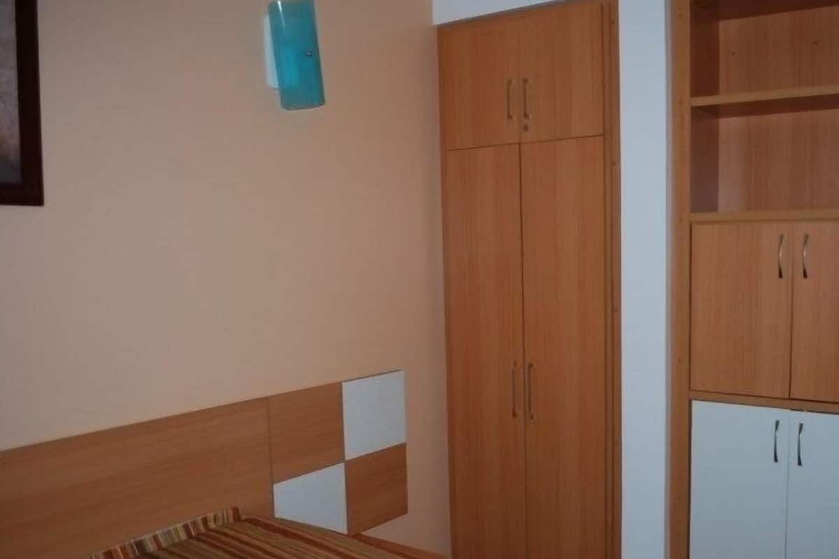Ein Schlafzimmer mit einem Bett, einem Kleiderschrank und einem kleinen Schrank.