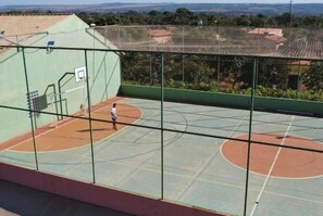 An outdoor basketball court with a netted enclosure, surrounded by a green fence. - Apartment diRoma Fiori - Achei Férias (Caldas Novas)