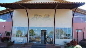 A building with a large glass facade, a prominent sign with the text "DIR", and a covered entrance area. - Apartment diRoma Fiori - Achei Férias (Caldas Novas)