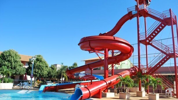 A water park with a large red water slide and a pool. - Apartment diRoma Fiori - Achei Férias (Caldas Novas)