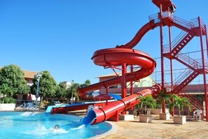 A water park with a large red water slide and a pool. - Apartment diRoma Fiori - Achei Férias (Caldas Novas)
