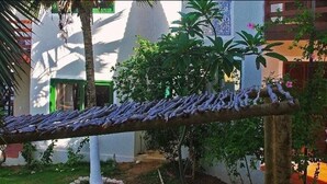 A wooden swing hanging over a garden with white buildings in the background.