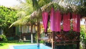 A pool area with a wooden deck and a thatched roof structure.