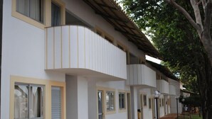 A row of white buildings with balconies, windows, and a paved walkway. - Apartment diRoma Resort - Achei Férias (Caldas Novas)
