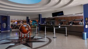 Un lobby amplio con una silla decorativa central, un mostrador de recepción y un tragaluz grande.