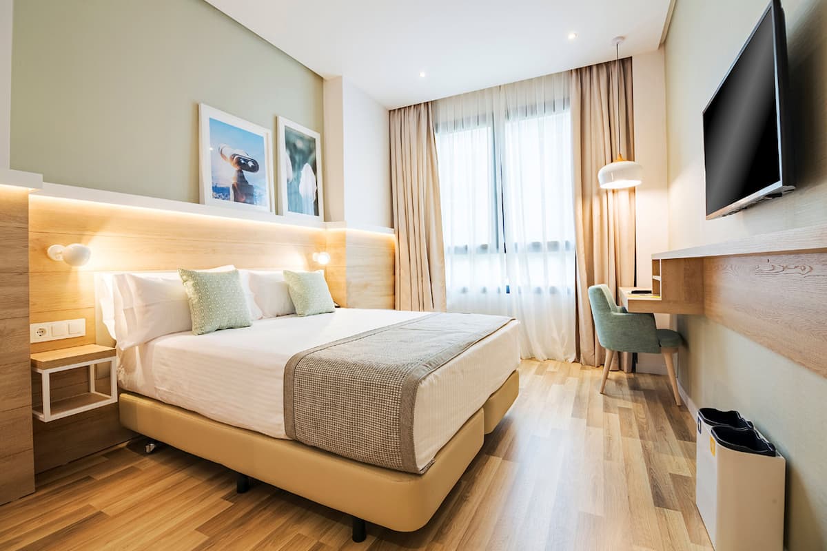 Une chambre d’hôtel moderne avec un grand lit, des tables de chevet, un bureau et une télévision.
