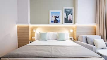 Habitación de hotel con una cama grande, un sofá, una mesita y una mesita de noche con lámpara.