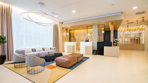 Un hall d’hôtel moderne avec un comptoir d’accueil, un canapé et une table basse.