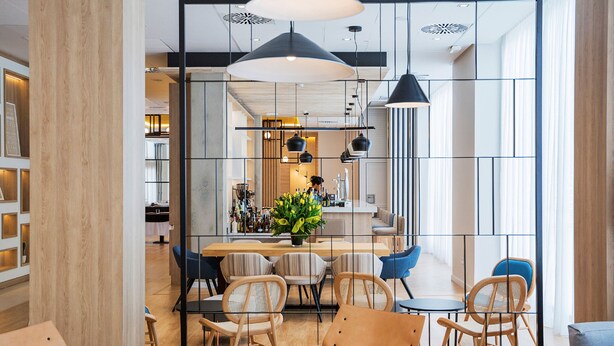 Un intérieur moderne avec un espace bar, des coins salon et une cuisine ouverte visible au fond.