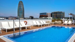 A rooftop pool with white lounge chairs, a lifebuoy, and a cityscape with modern buildings in the background. - ZT The Golden Hotel Barcelona (Barcelona)