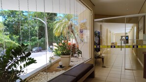 A hotel lobby with a large window, a bench, and a tiled floor. - Royal Residence - Achei Férias (Caldas Novas)