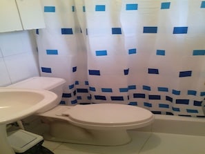 Un bagno con il water, un lavandino e una tenda per la doccia.