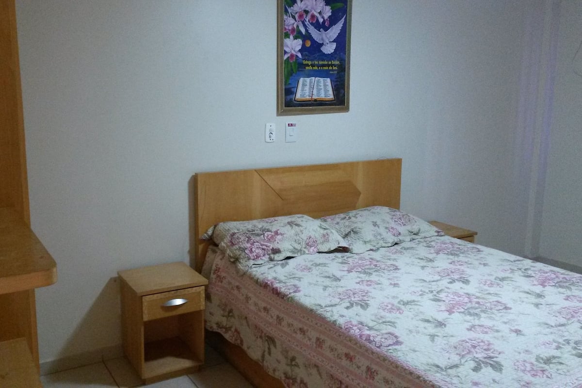 A bedroom with a wooden bed, a nightstand, and a poster on the wall.