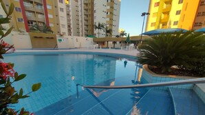 A swimming pool with tiled edges, surrounded by a low wall and a railing. - Vitória das Thermas - Achei Férias (Caldas Novas)