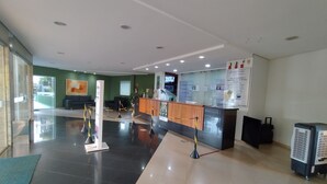 A reception area with a wooden counter, a seating area with a sofa, and a glass partition. - Vitória das Thermas - Achei Férias (Caldas Novas)