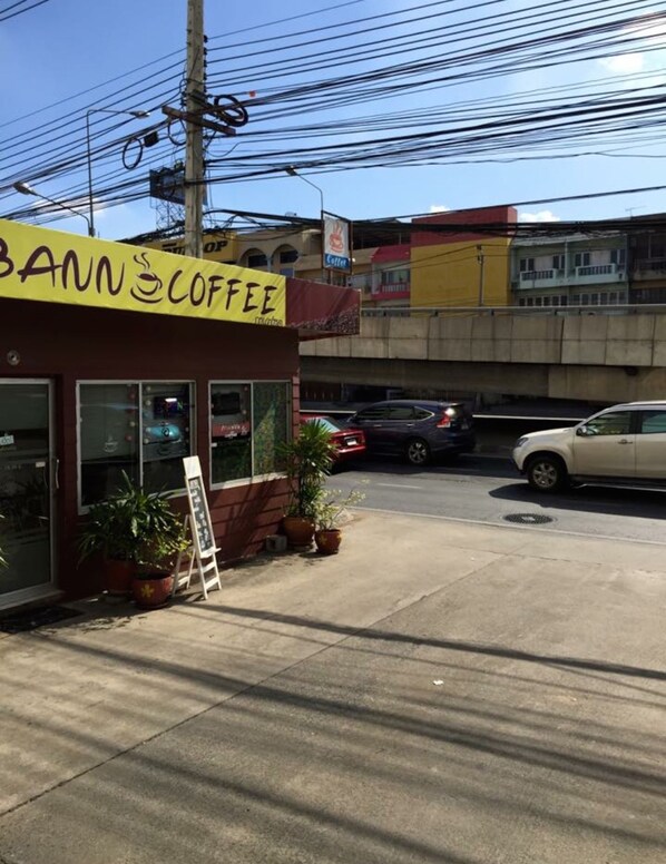 A coffee shop named 'BANN COFFEE' with a clear storefront, potted plants, and a sidewalk.