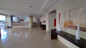 Un hall d’entrée spacieux comprenant un comptoir d’accueil, une grande peinture abstraite et un espace d’accueil moderne.