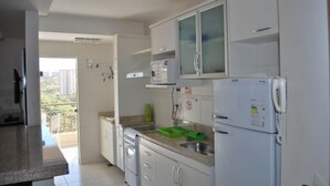 Une cuisine avec des meubles blancs, un réfrigérateur, un four à micro-ondes et un évier.