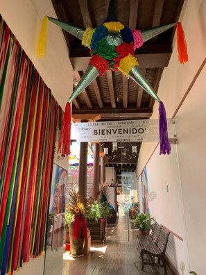 A hallway with a colorful welcome sign, striped walls, and a bench. - Hotel Villa de Flores (Uruapan)