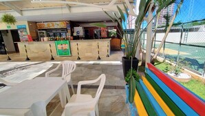 A restaurant with a counter, chairs, and a view of a basketball court.