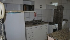 A kitchen with white cabinets, a microwave, a stove, and a sink.