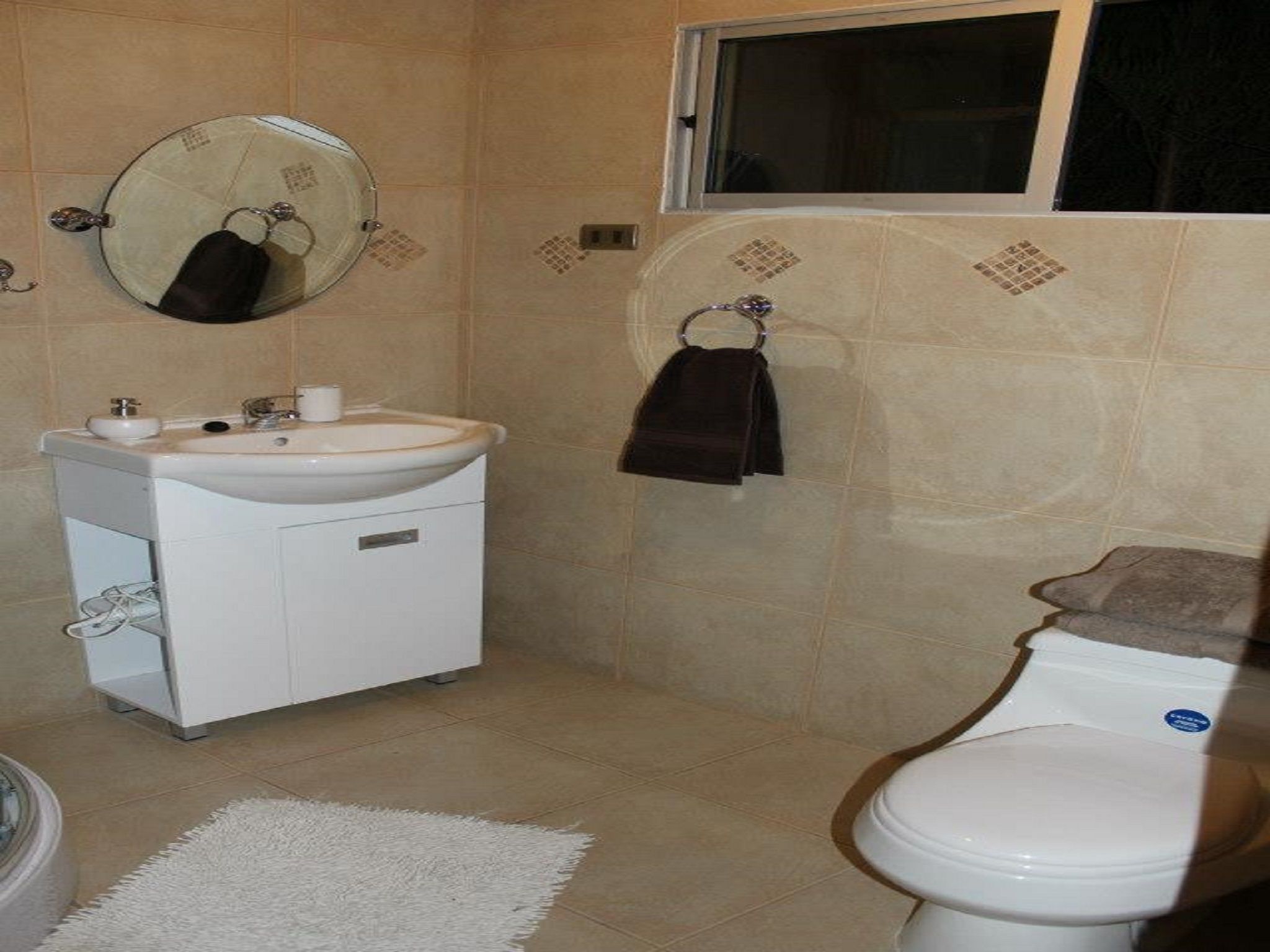 A bathroom with a white sink, mirror, and toilet.