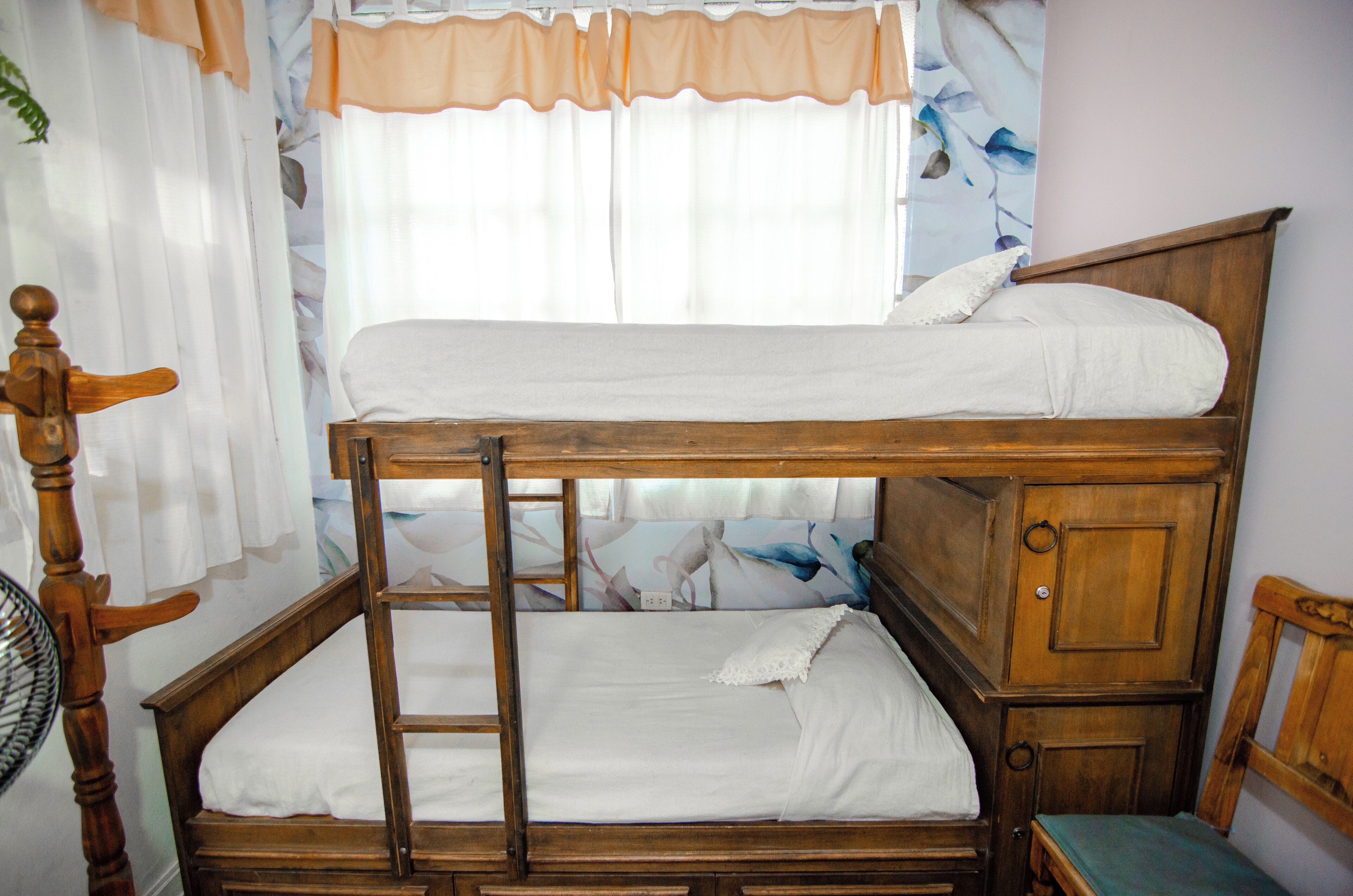 A bunk bed with a wooden frame, a ladder, and a small cabinet.
