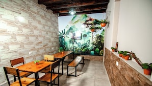 Een restaurant met bakstenen muren, houten tafels en stoelen, en een muurschildering van een oerwoud.