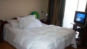 A neatly made bed with white bedding in a hotel room.
