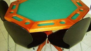 A round pool table with a green felt surface and a wooden border, surrounded by black chairs.